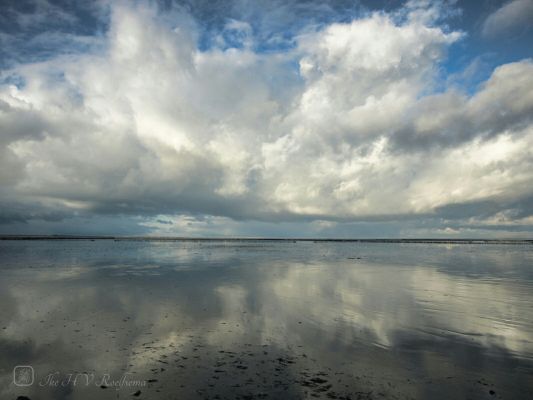Wolken weerspiegeld in het Wad